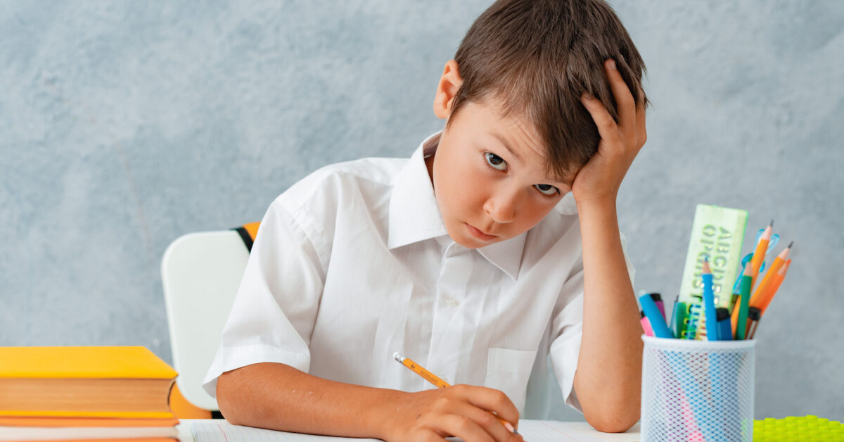 Back to school. Happy smiling student draws at the Desk. A schoolboy solves his homework. A boy from elementary school.